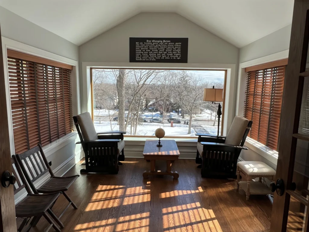 Restored sun porch with chairs arranged around a central table and a snowy view outside.