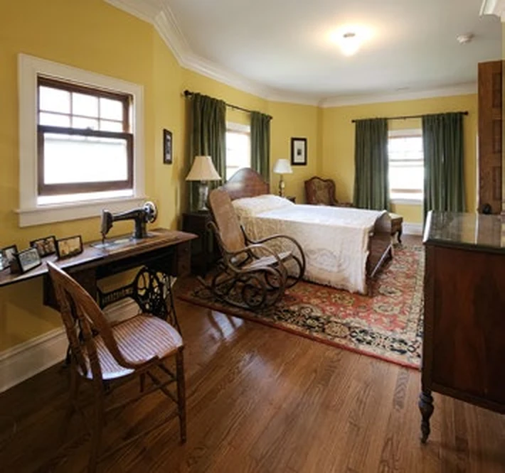 Bedroom Interior at the Harris Home Restored bedroom with wood floor, bed, desk, and period furnishings.