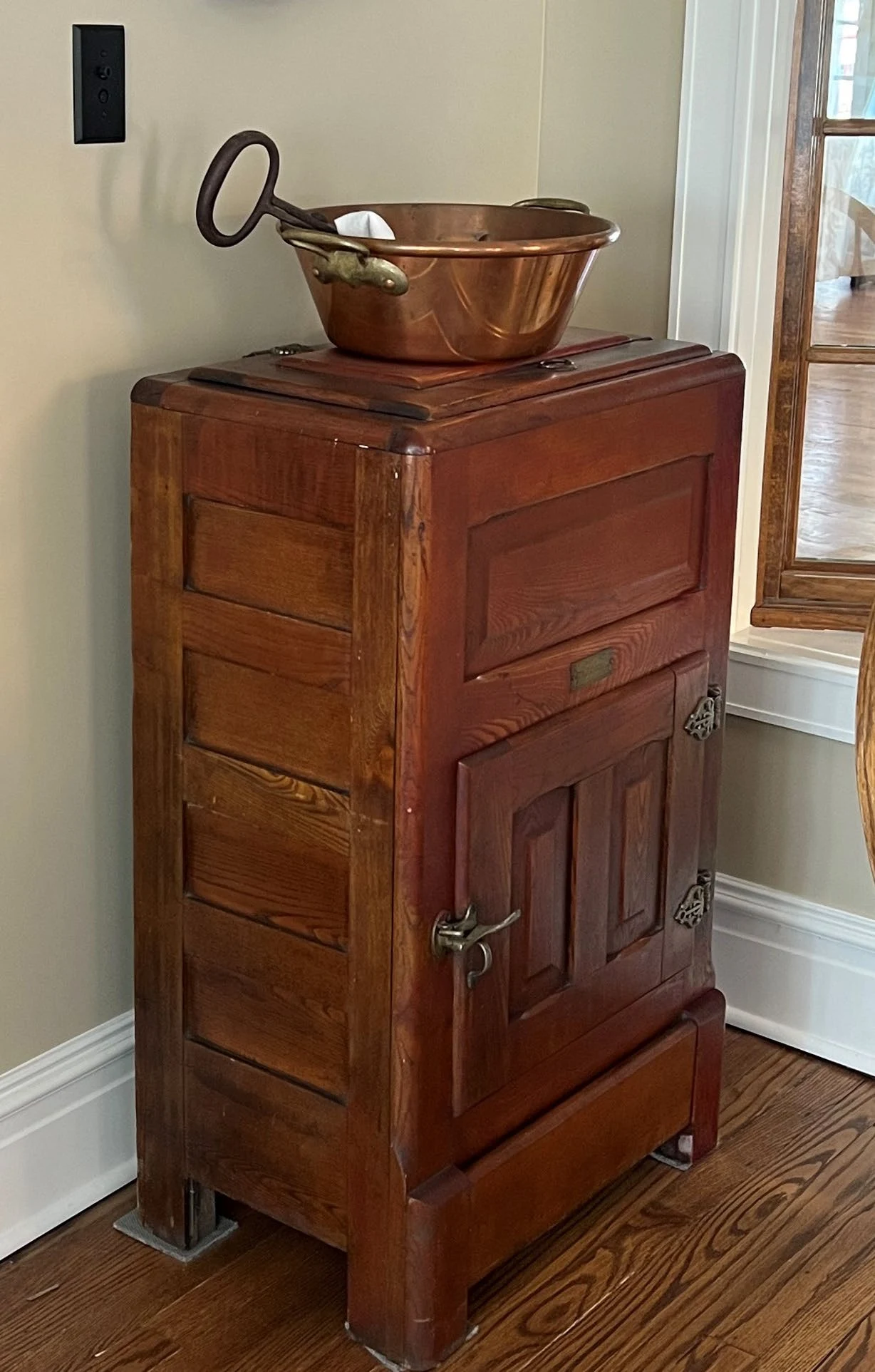 Period Cabinet and Copper Vessel Tall wooden cabinet topped with a copper vessel in a restored room.
