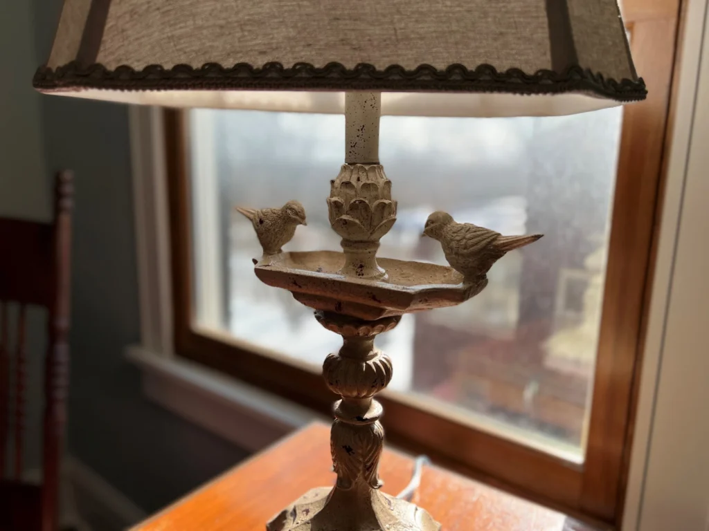 Period Table Lamp Detail Close view of a period-style table lamp beside a window.