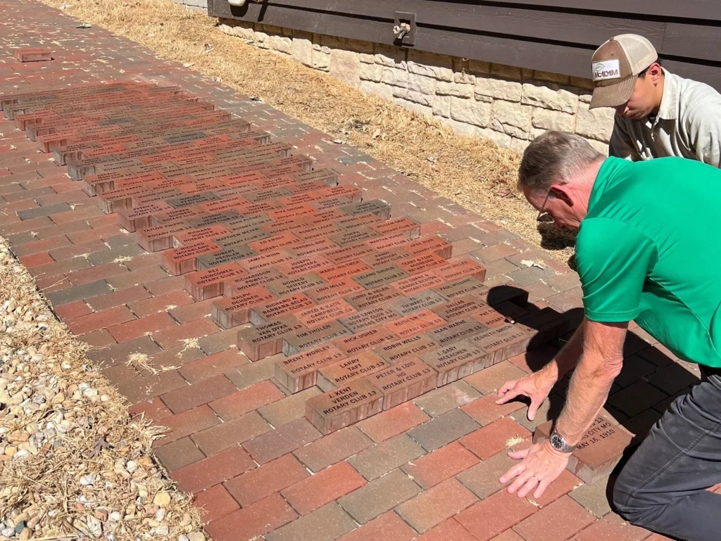 People installing personalized bricks along the walkway beside the Harris Home.